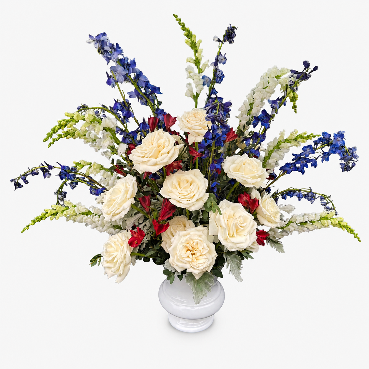 Floral arrangement with white, red, and blue flowers in a white vase on a white background