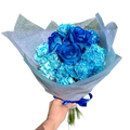 Bouquet of blue roses and blue carnations held by a hand against a white background