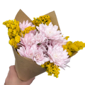 Bouquet of pink and yellow flowers wrapped in brown paper held by a hand on a white background