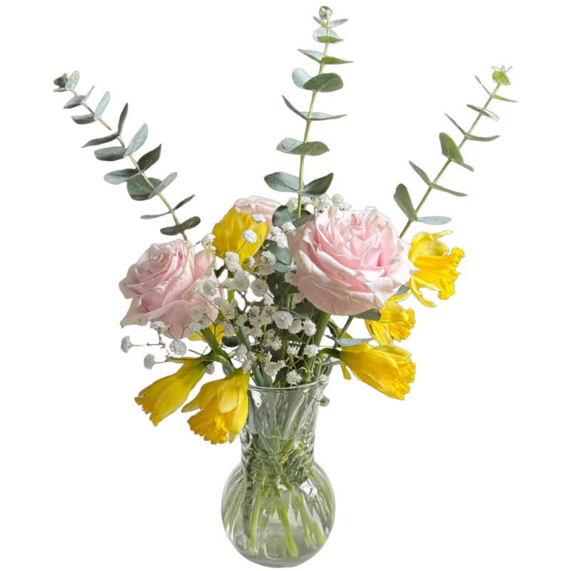 Bouquet of pink and yellow flowers in a clear glass vase on a white background